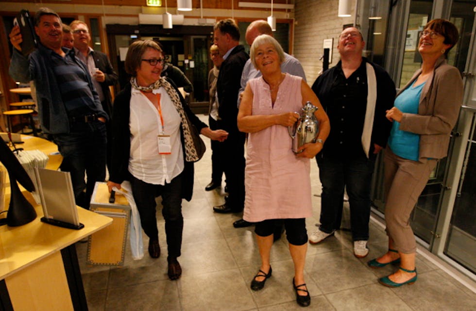 Glade Høgre-medlem samt eit par spente lokalpolitikarar sjekkar storskjermen på rådhuset.