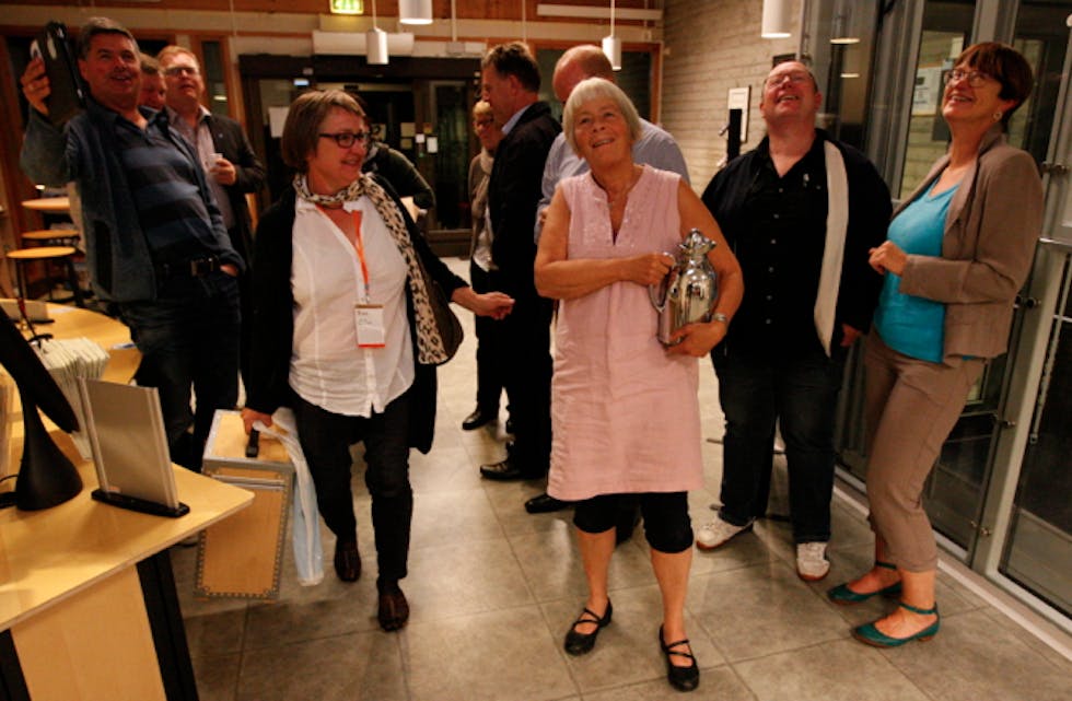 Glade Høgre-medlem samt eit par spente lokalpolitikarar sjekkar storskjermen på rådhuset.