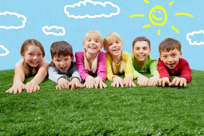 Group of happy children lying on a grass and stretching their hands