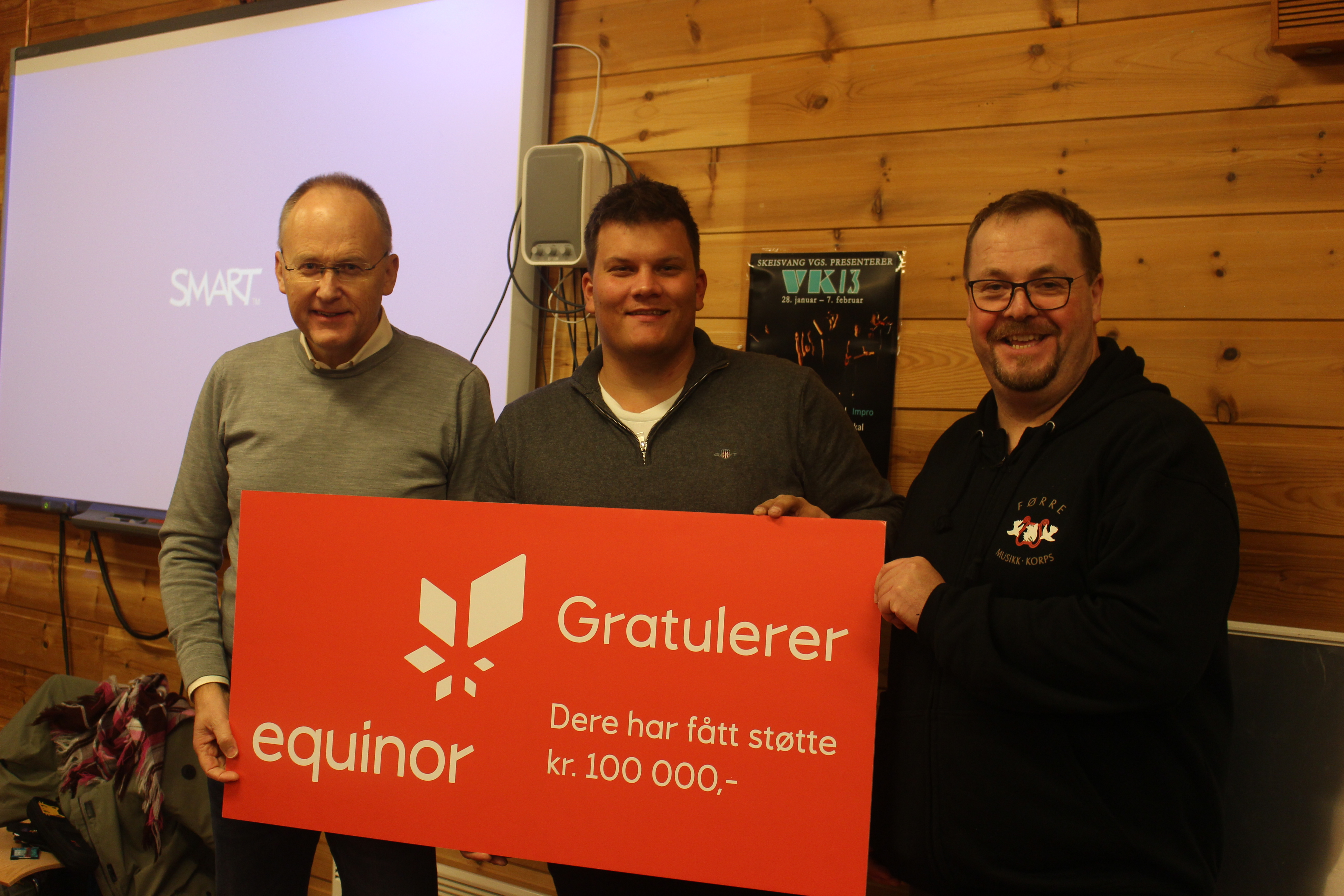 Kommunikasjonssjef i Equinor overleverte sjekken til styreleiar Dag Magne Torland og korpsleiar Jan Fitjar.