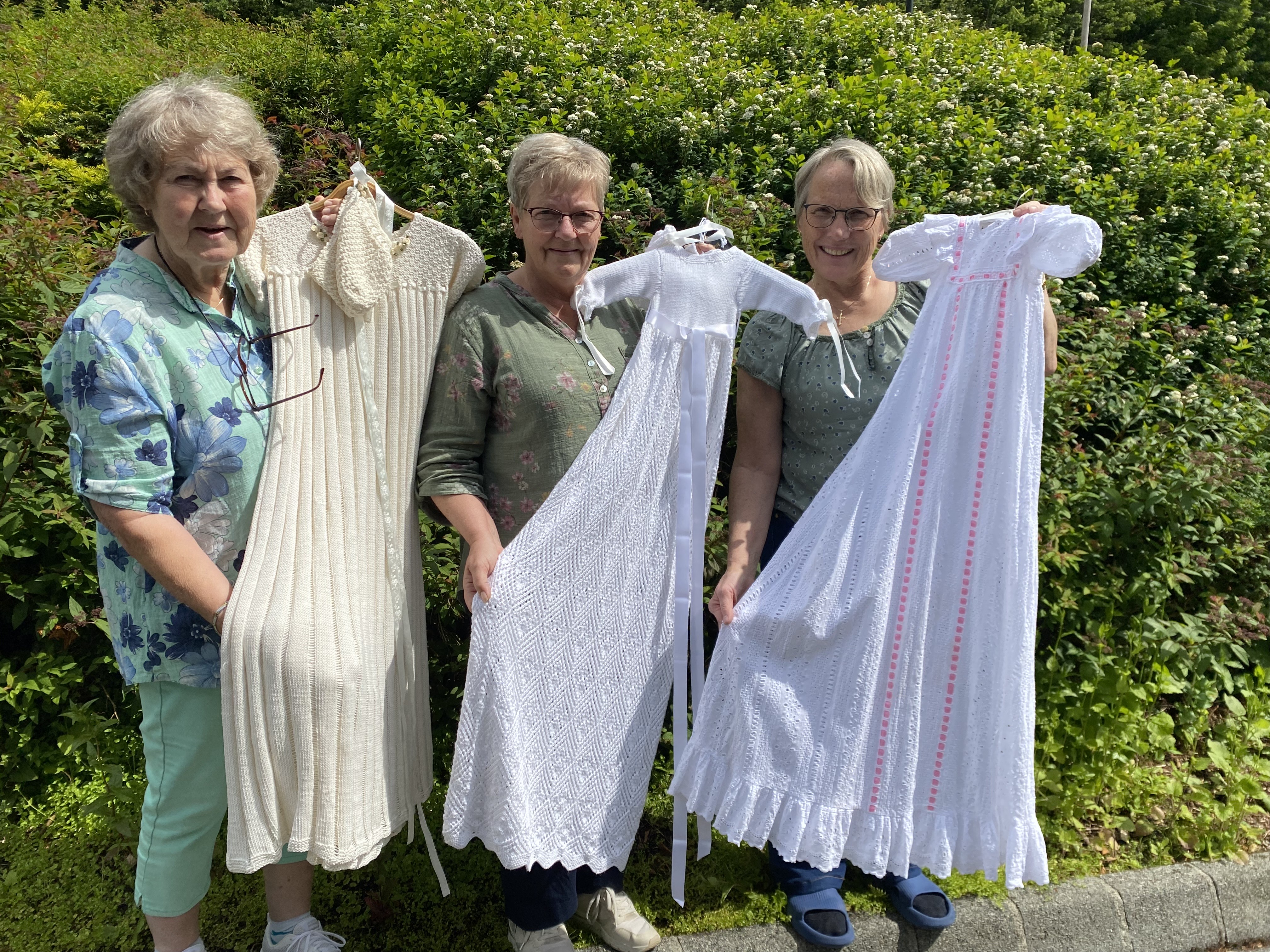 Inger Pedersen-Espevold, leiar i Tysvær Sanitetsforening, og Gerd Borgny Rossebø overleverer tre dåpskjolar til Tysvær sokn v/Marit Sofie Teistedal Vikre (t.h). Kjolane er til gratis utlån for dei som skal døype barna sine.