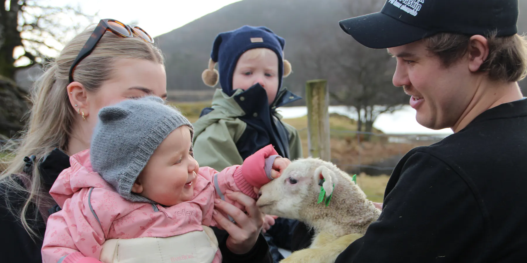 Kornelia (9 mnd) møter et av årets første lam på familiegården i Grinde. Her sammen med mamma, Camilla, broren Berdinius og pappa Tollak Emil.